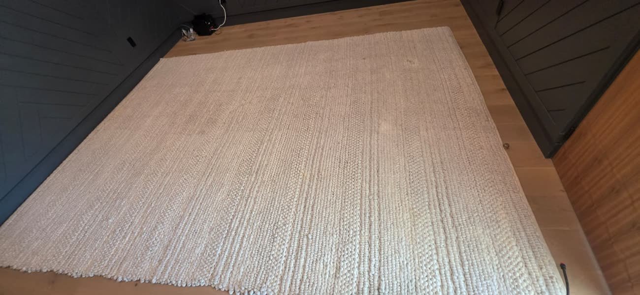 Large woven area rug laid out on hardwood flooring after on-site cleaning